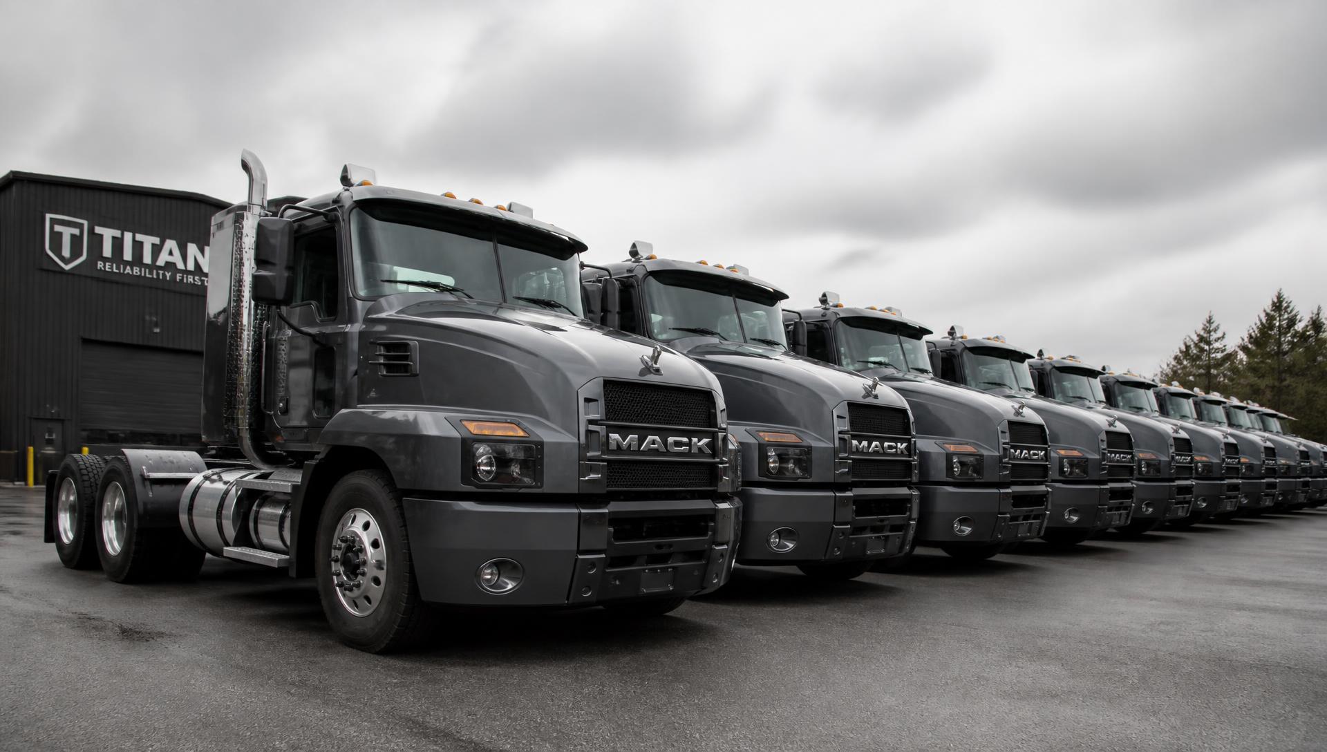 Row of commercial diesel trucks lined up at a company fleet yard